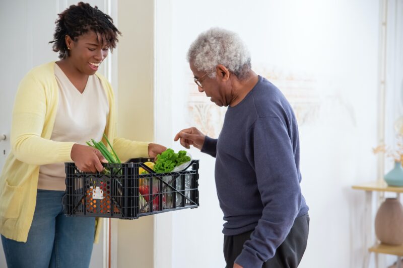 Woman providing older male fresh vegetables 
