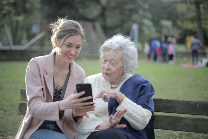 Older woman and younger woman sitting on bench together